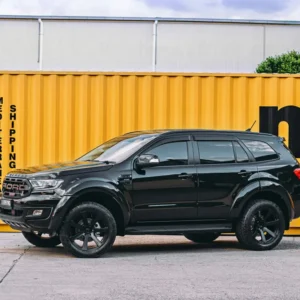 Black Ford Everest 2015–2021 with EGR no-drill fender flares and off-road wheels parked in front of a yellow shipping container.
